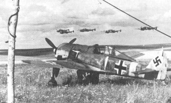 FW190-F8tp-I.1.Unknown-Unit-White1-w-External-Engine-Air-Intakes-For-More-Supercharger-Airflow-&-More-Rear-Cylinder-Cooling-&-Sand-Filters-&-No-Gear-Wheel-Covers-&-w-Five-Me110s-Passing-Low-Overhead-In-Formation-Romania-July-1944-56.jpg (22K)